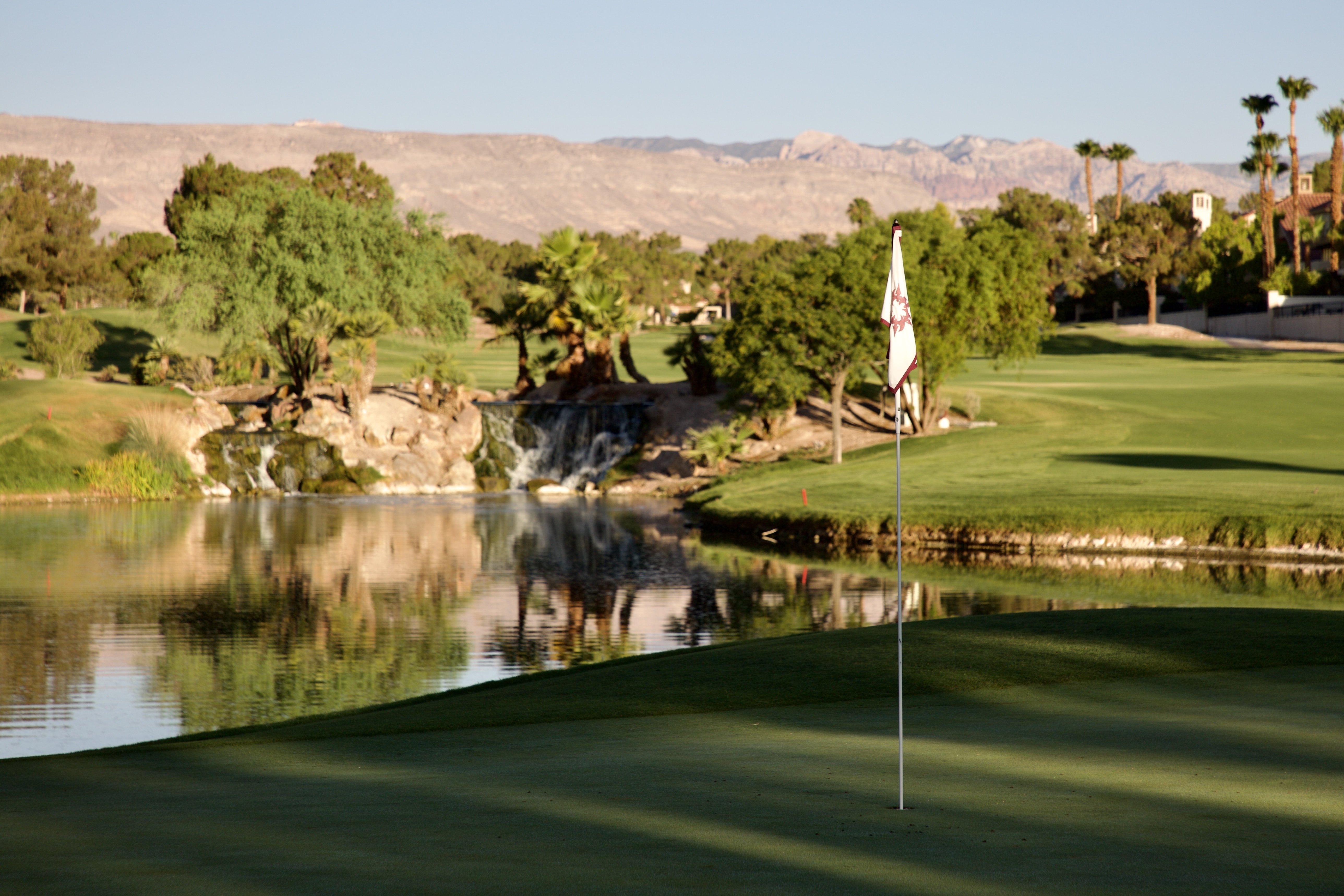 Putting green and flag with a rocky waterfall cascading into a reflecting pond
