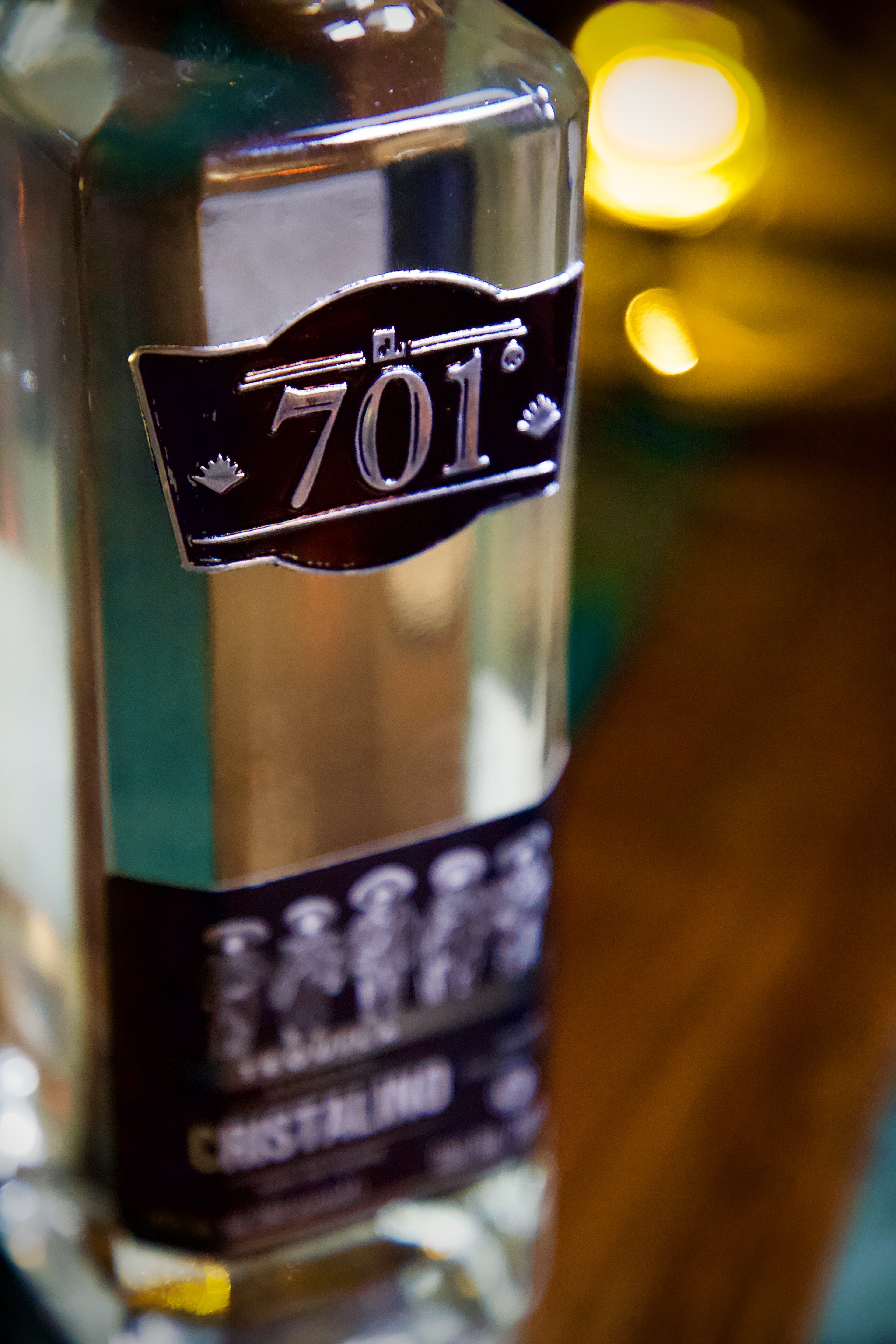 Extreme close-up of the embossed silver and black 701 crest on a clear tequila bottle